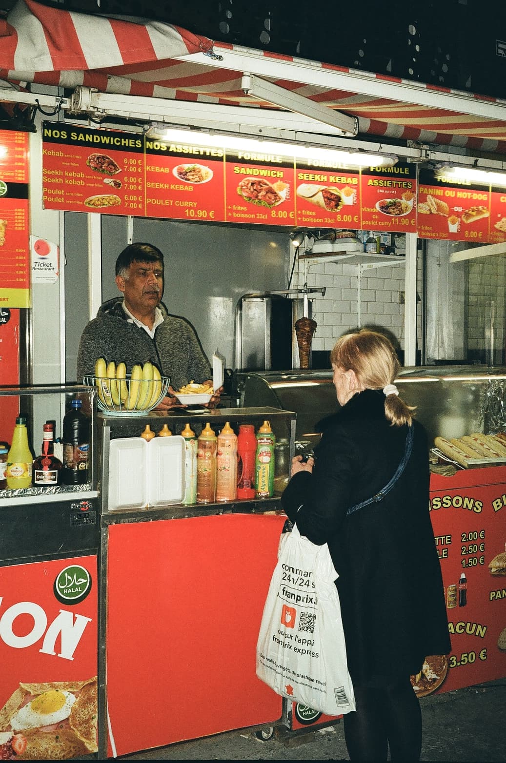 Barthelemy de Mazenod | People of Paris | An old woman ordering a kebab in an open air kebab shop